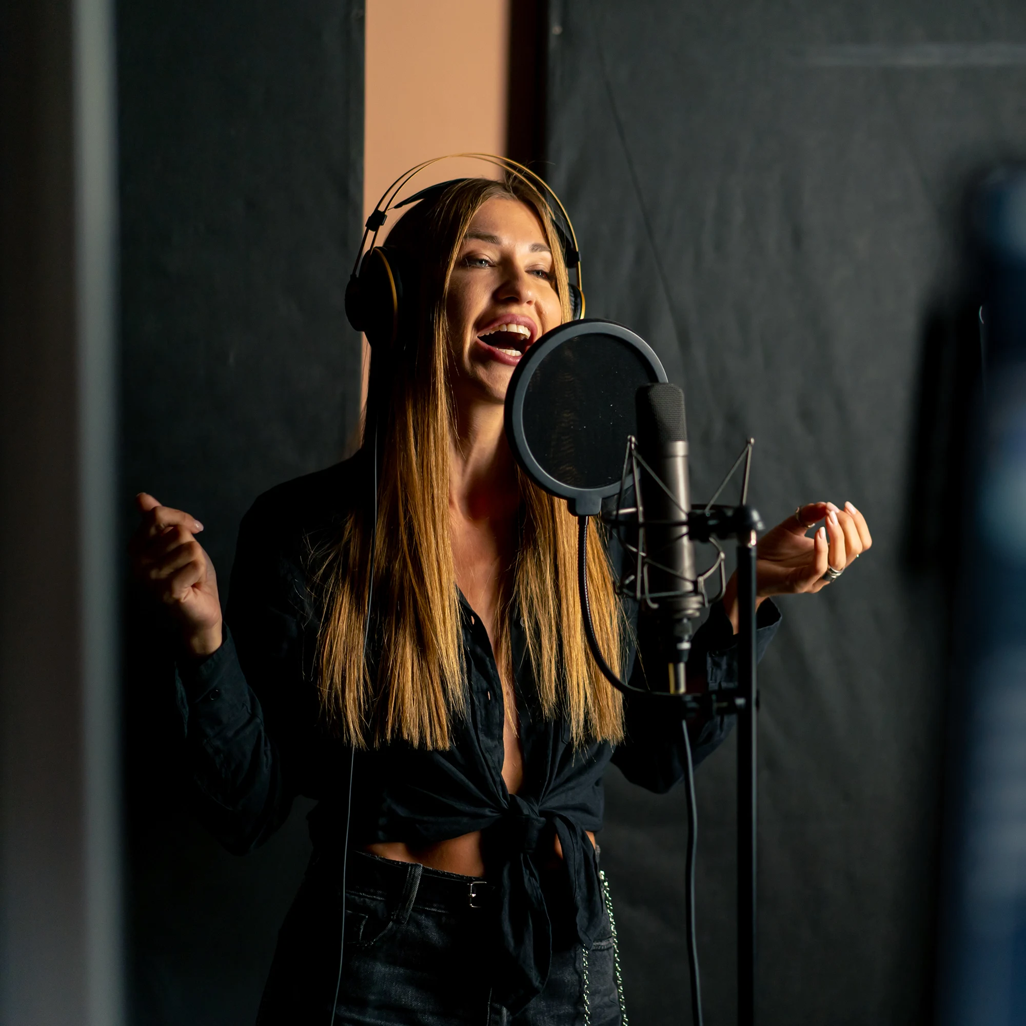 A young woman singing in a recording studio with headphones